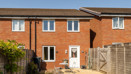 Rear view of a red brick house with patio doors and enclosed garden.