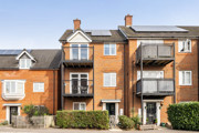 Apartment building with balconies, brick façade and landscaped frontage.