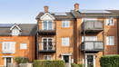 Apartment building with balconies, brick façade and landscaped frontage.