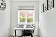 Dining area with a table and chairs positioned beneath a window.