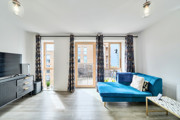Living room with blue sofa and doors opening to a balcony.