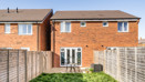 Rear view of a red-brick house with fenced garden and patio doors.