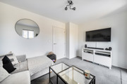 Living room with sofas, a wall-mounted television and glass coffee table.