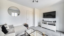 Living room with sofas, a wall-mounted television and glass coffee table.