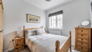 Bedroom with wooden bed frame, drawers, and window with blinds.
