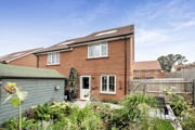 Rear view of semi-detached red brick house with garden and patio doors.