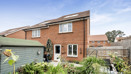 Rear view of semi-detached red brick house with garden and patio doors.