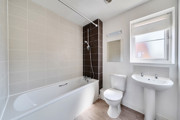 Bathroom with bath, toilet and pedestal sink.