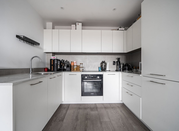 White fitted kitchen with integrated oven, hob, cupboards and worktops. (1)