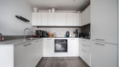 White fitted kitchen with integrated oven, hob, cupboards and worktops. (1)