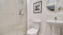 Ensuite with glass shower, toilet, sink, and round mirror.