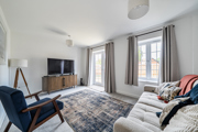 Living room with sofa, TV, rug, window and patio doors with curtains.