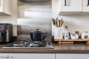 Gas hob with cooking pot beside kitchen utensils and small appliances.