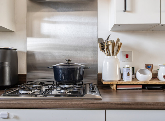 Gas hob with cooking pot beside kitchen utensils and small appliances.