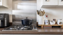 Gas hob with cooking pot beside kitchen utensils and small appliances.