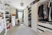 Second bedroom with shelving, hanging clothes and a washing machine.