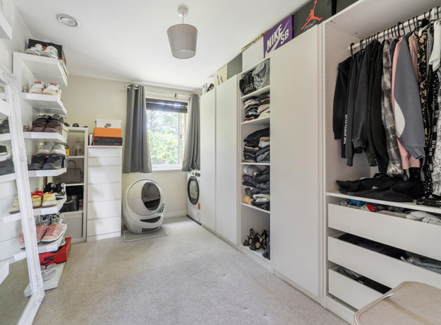Second bedroom with shelving, hanging clothes and a washing machine.
