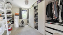 Second bedroom with shelving, hanging clothes and a washing machine.