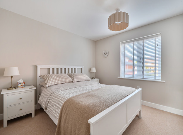 Bedroom with double bed, bedside tables and window with blinds.