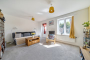 Living room with sofa, shelving, television and patio door to the garden.