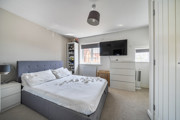 Spacious bedroom with double bed, wall-mounted TV, and neutral decor.