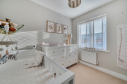 Bedroom with a cot, chest of drawers and window with blinds.