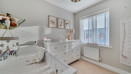 Bedroom with a cot, chest of drawers and window with blinds.