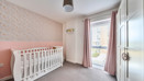 Nursery room with cot, patterned feature wall,wardrobe and large window.