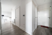 Entrance hallway with white doors, wood flooring and open-plan living area.