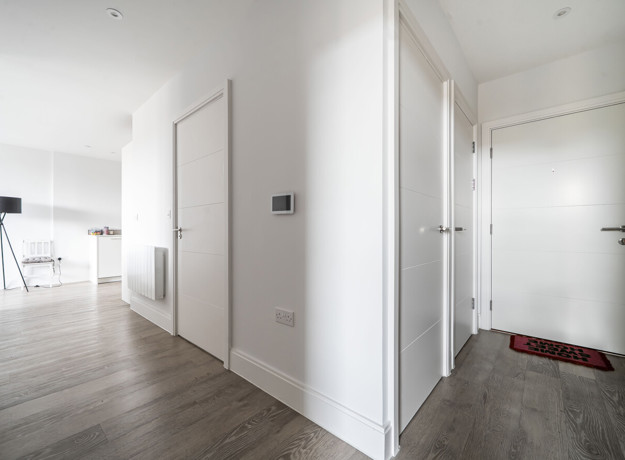 Entrance hallway with white doors, wood flooring and open-plan living area.