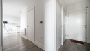 Entrance hallway with white doors, wood flooring and open-plan living area.