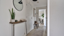 Hallway with console table, mirror, plant, and open doorway to living space.