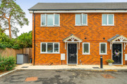Front view of a red brick semi-detached house with black entrance door.