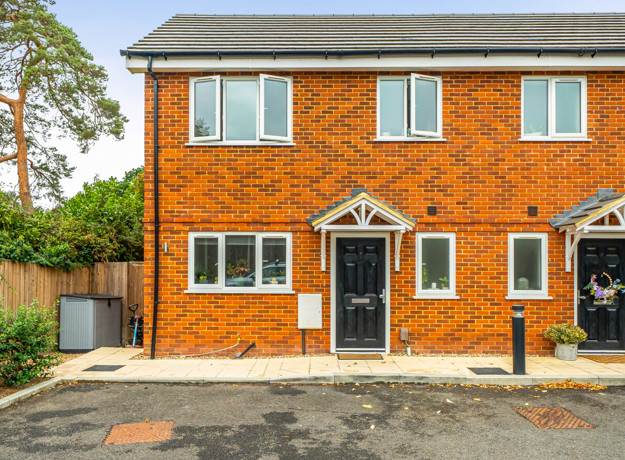 Front view of a red brick semi-detached house with black entrance door.