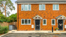 Front view of a red brick semi-detached house with black entrance door.