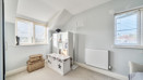 Bedroom with shelving unit, radiator and windows on two walls.