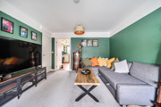 Living room with grey sofa, wall-mounted TV, green feature wall and coffee table.