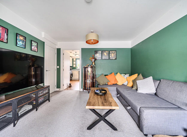 Living room with grey sofa, wall-mounted TV, green feature wall and coffee table.