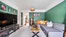 Living room with grey sofa, wall-mounted TV, green feature wall and coffee table.