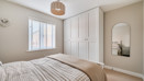 Bedroom with fitted wardrobes, wall mirror and window with blinds.
