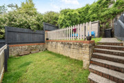 Terraced back garden with grass lawn, steps, retaining wall and shed.