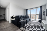 Open-plan living area with corner sofa, patterned rug and balcony doors.