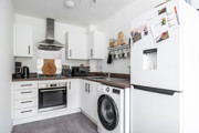 White kitchen with fitted appliances, washing machine and refrigerator.