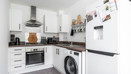 White kitchen with fitted appliances, washing machine and refrigerator.