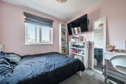 Bedroom with a double bed, shelving unit, desk and wall-mounted television.