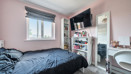 Bedroom with a double bed, shelving unit, desk and wall-mounted television.