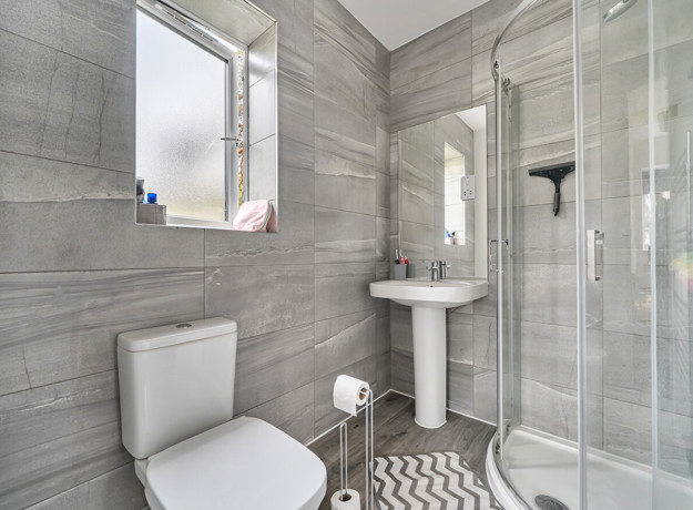 Ensuite with a toilet, pedestal sink and glass shower enclosure.