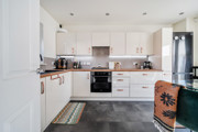 White kitchen with integrated appliances, dining table and tiled floor.