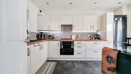 White kitchen with integrated appliances, dining table and tiled floor.