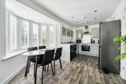 Open-plan kitchen and dining area with table, chairs and window blinds.